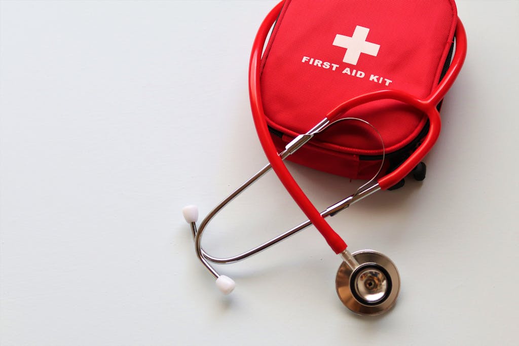 A red first aid kit paired with a stethoscope, signifying healthcare and medical treatment essentials.